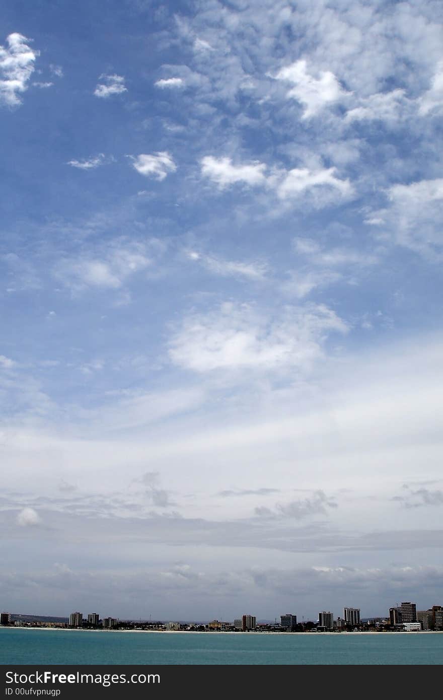 A cityscape with the ocean and a lot of sky.