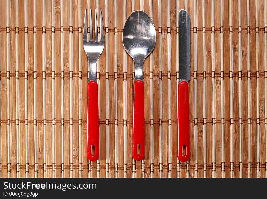 Set of spoon, fork and knife on bamboo background