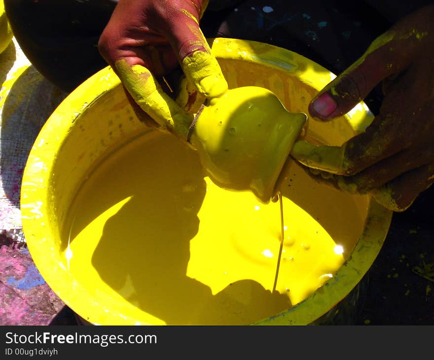 A man coloring pots into yellow color. A man coloring pots into yellow color