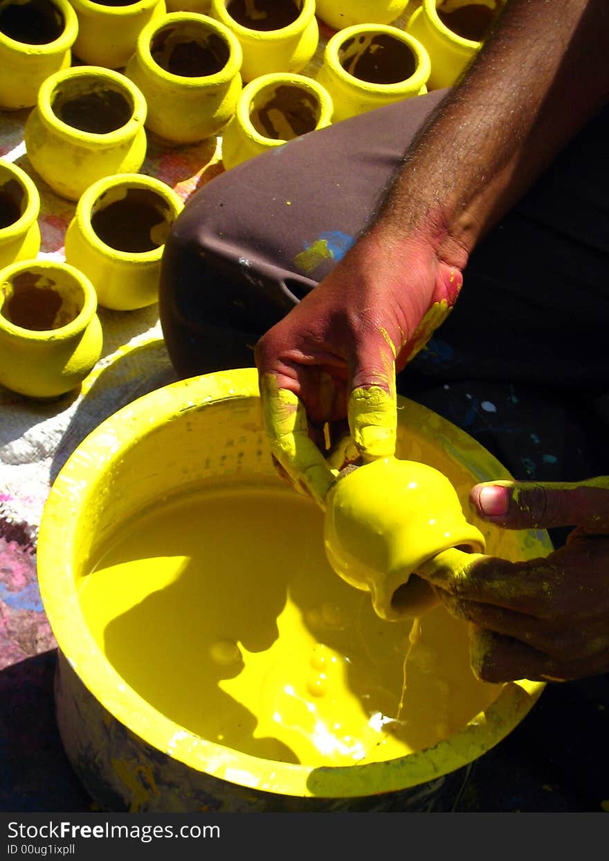 A man working and coloring yellow colored pots. A man working and coloring yellow colored pots