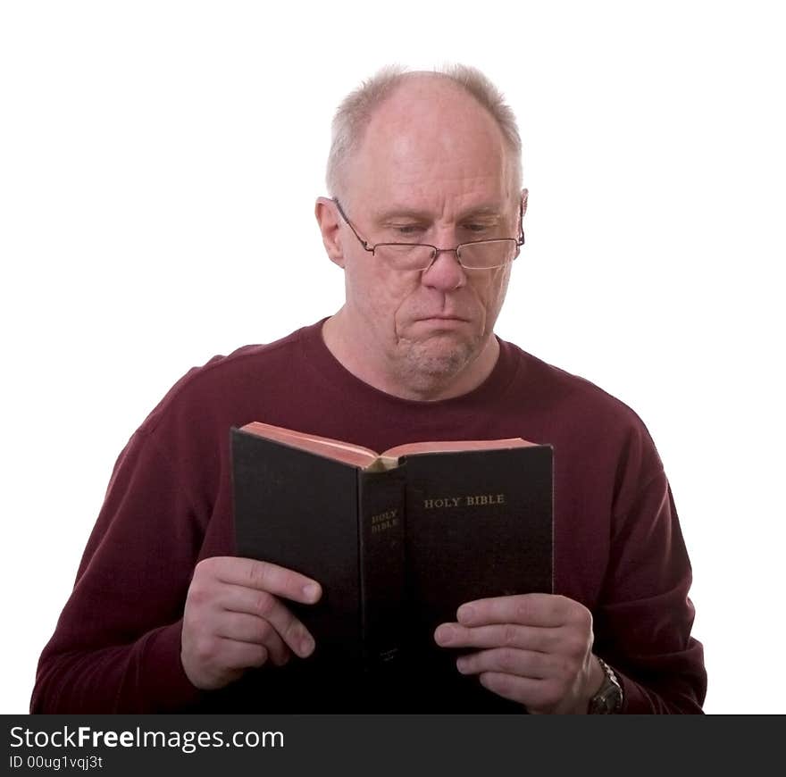 An older bald man in a red shirt and glasses reading the bible on a white background. An older bald man in a red shirt and glasses reading the bible on a white background