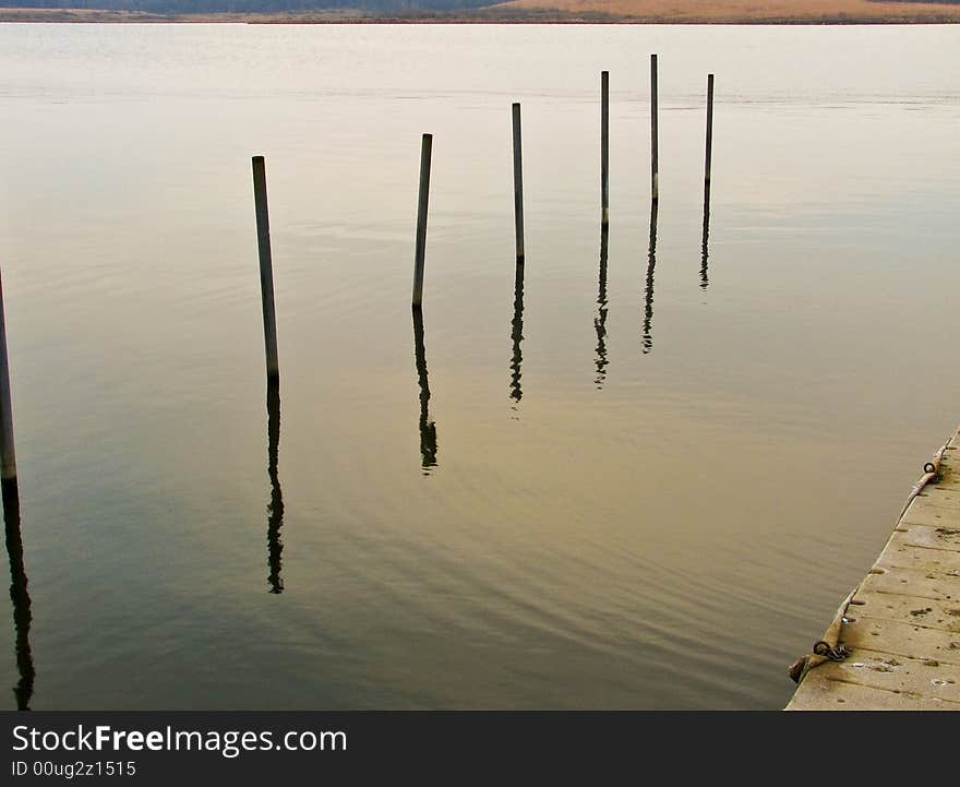 Poles sticking out of lake near pier. Poles sticking out of lake near pier