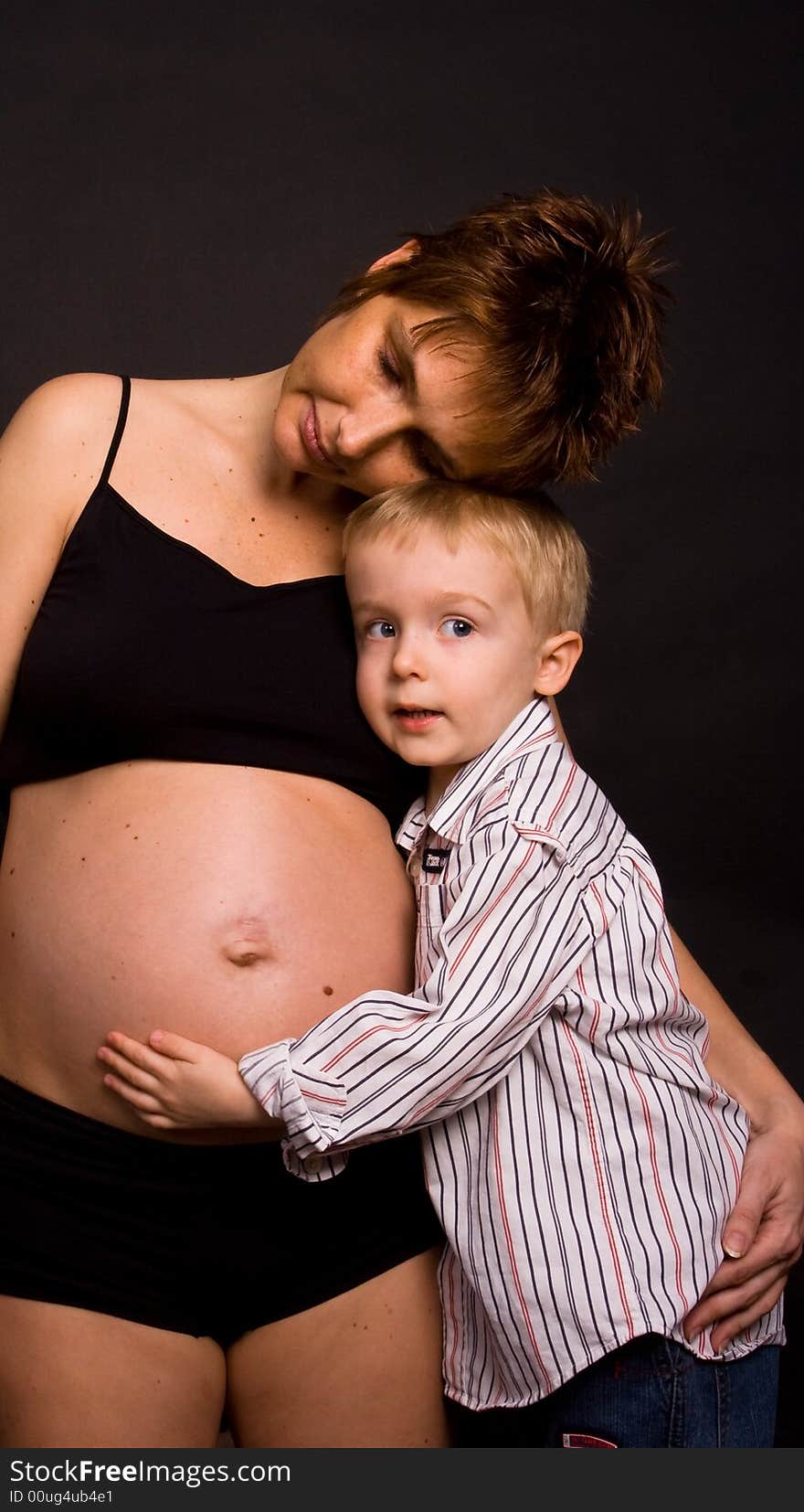 A pregnant woman with her child holding her belly. A pregnant woman with her child holding her belly