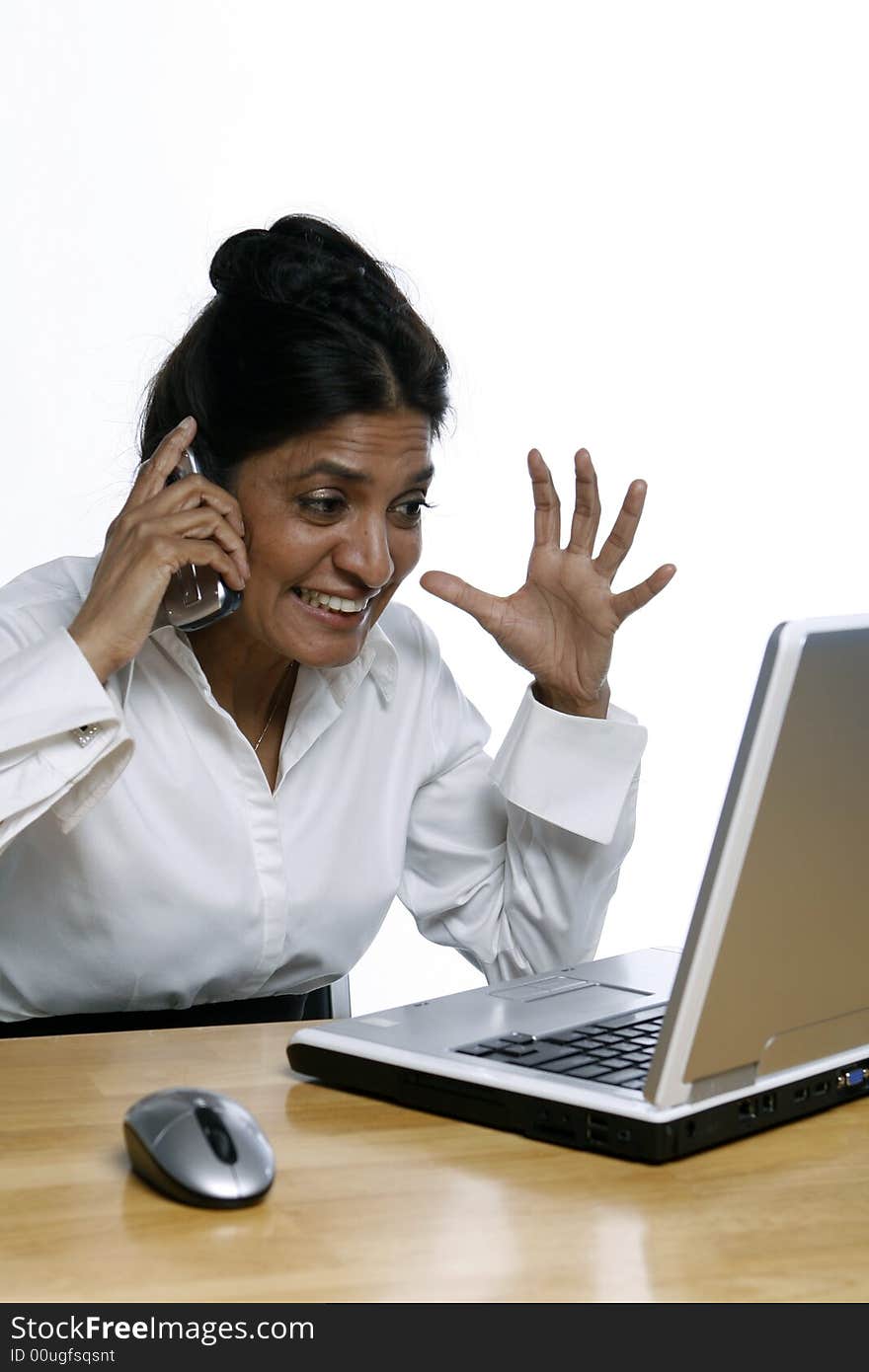 Vertical shot of an Indian woman at her laptop while on the phone. Vertical shot of an Indian woman at her laptop while on the phone