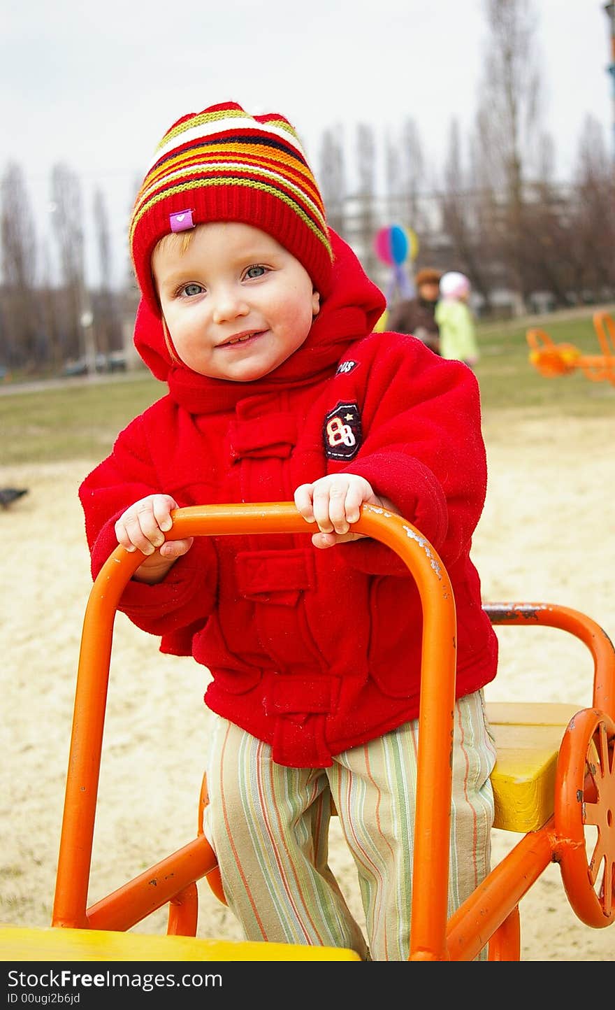 Laughing girl in a red jacket goes for a drive on a swing. Laughing girl in a red jacket goes for a drive on a swing