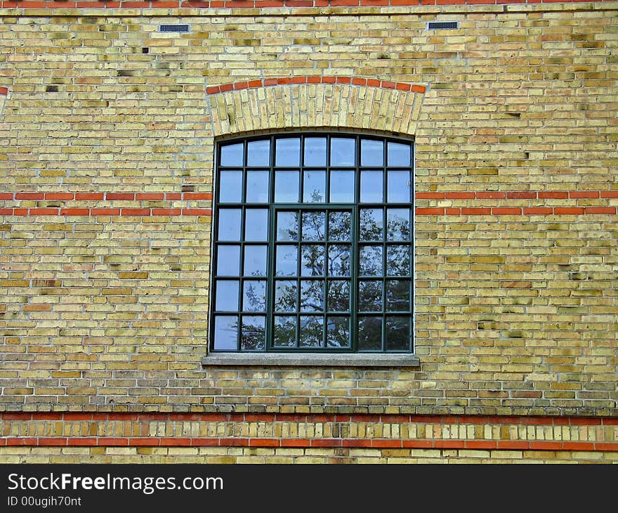 Yellow earth colors bricks wall and a window with reflection