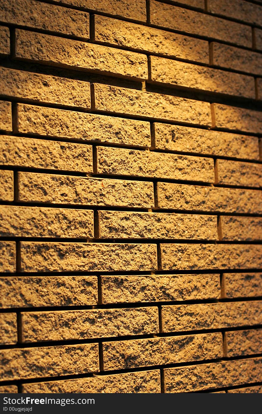 A wall of yellow bricks lit from the top with a spot light.