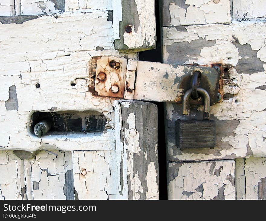 A shot of an isolated unlocked padlock, securing a shed, made of wood, with white peeling paint. A shot of an isolated unlocked padlock, securing a shed, made of wood, with white peeling paint.