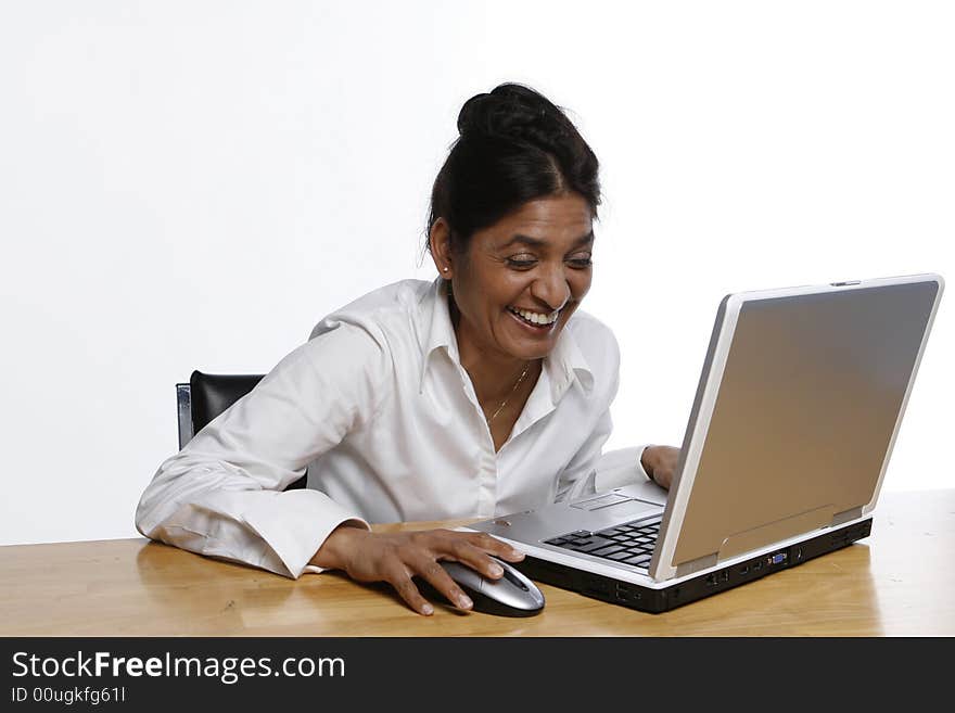 Indian woman laughing heartily at her laptop. Indian woman laughing heartily at her laptop