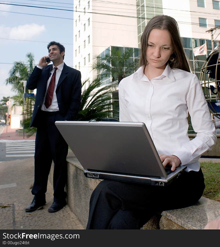 A professional man and woman working casually outside. A professional man and woman working casually outside.