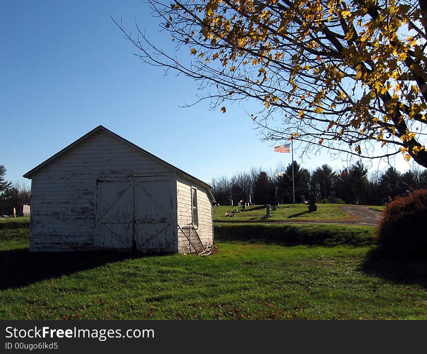 White Shed by Cemetery under a Blue Sky