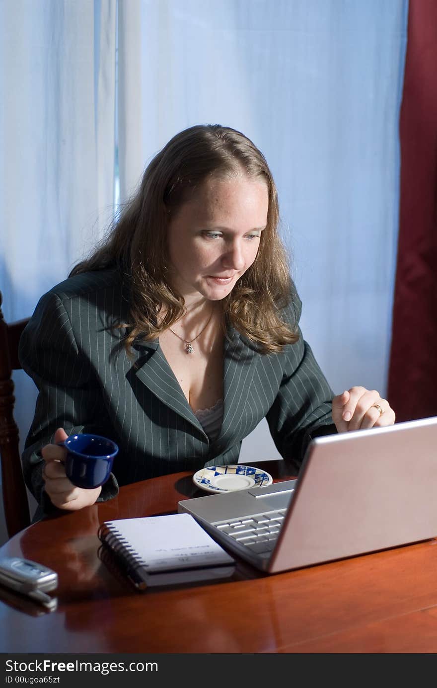 A woman sitting in suit drinking tea and browsing the internet. A woman sitting in suit drinking tea and browsing the internet.