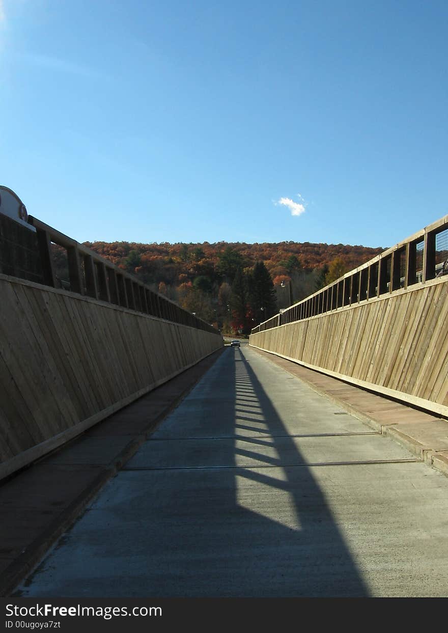 A shot of a footbridge, with trees and a clear blue sky at the vanishing point. A shot of a footbridge, with trees and a clear blue sky at the vanishing point.