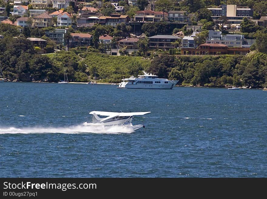 Small aircraft landing on water in sydney harbor australia and yacht and buildings in background. Small aircraft landing on water in sydney harbor australia and yacht and buildings in background