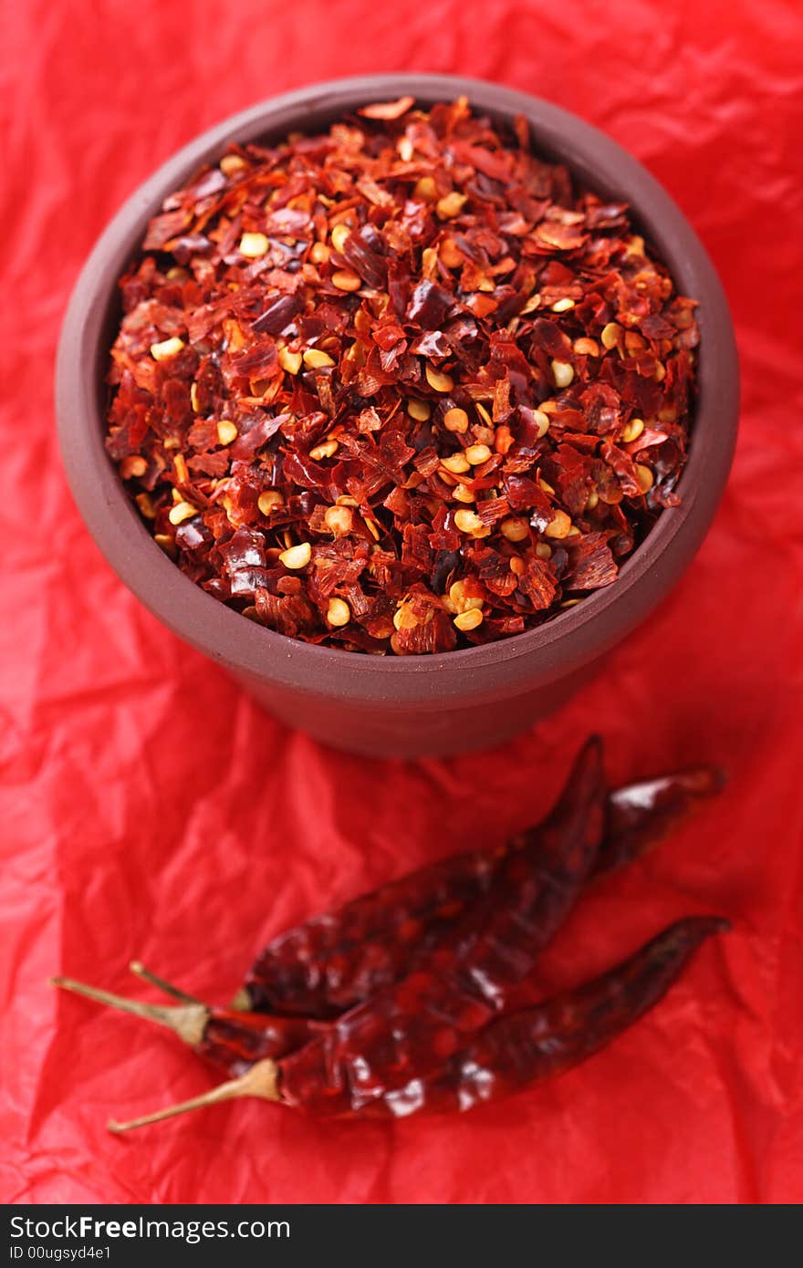 Hot Red Chilli Chillies crushed pepper in teracotta pot on red Background, Shallow DOF. Hot Red Chilli Chillies crushed pepper in teracotta pot on red Background, Shallow DOF