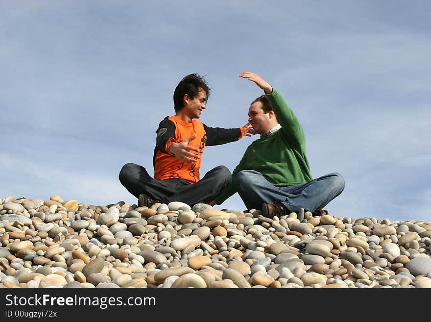 Two friends hugging at the beach isolated in blue sky background