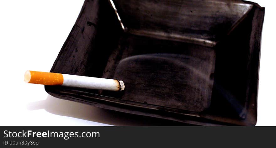 Shot of a cigarette lit in an ashtray. Shot of a cigarette lit in an ashtray