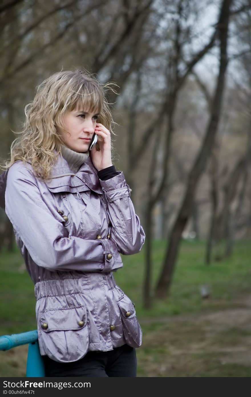 Girl speaks by phone in park. Girl speaks by phone in park