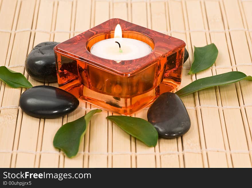 Spa stones with candle and green leaves on bamboo. Spa stones with candle and green leaves on bamboo