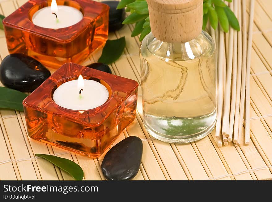 Aromatherapy bottle with sticks, stones, candles and green leaves on bamboo. Aromatherapy bottle with sticks, stones, candles and green leaves on bamboo