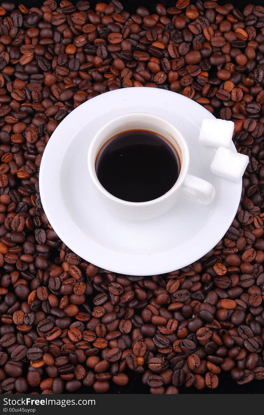 Fragrant fried coffee beans with a cup of coffee on top