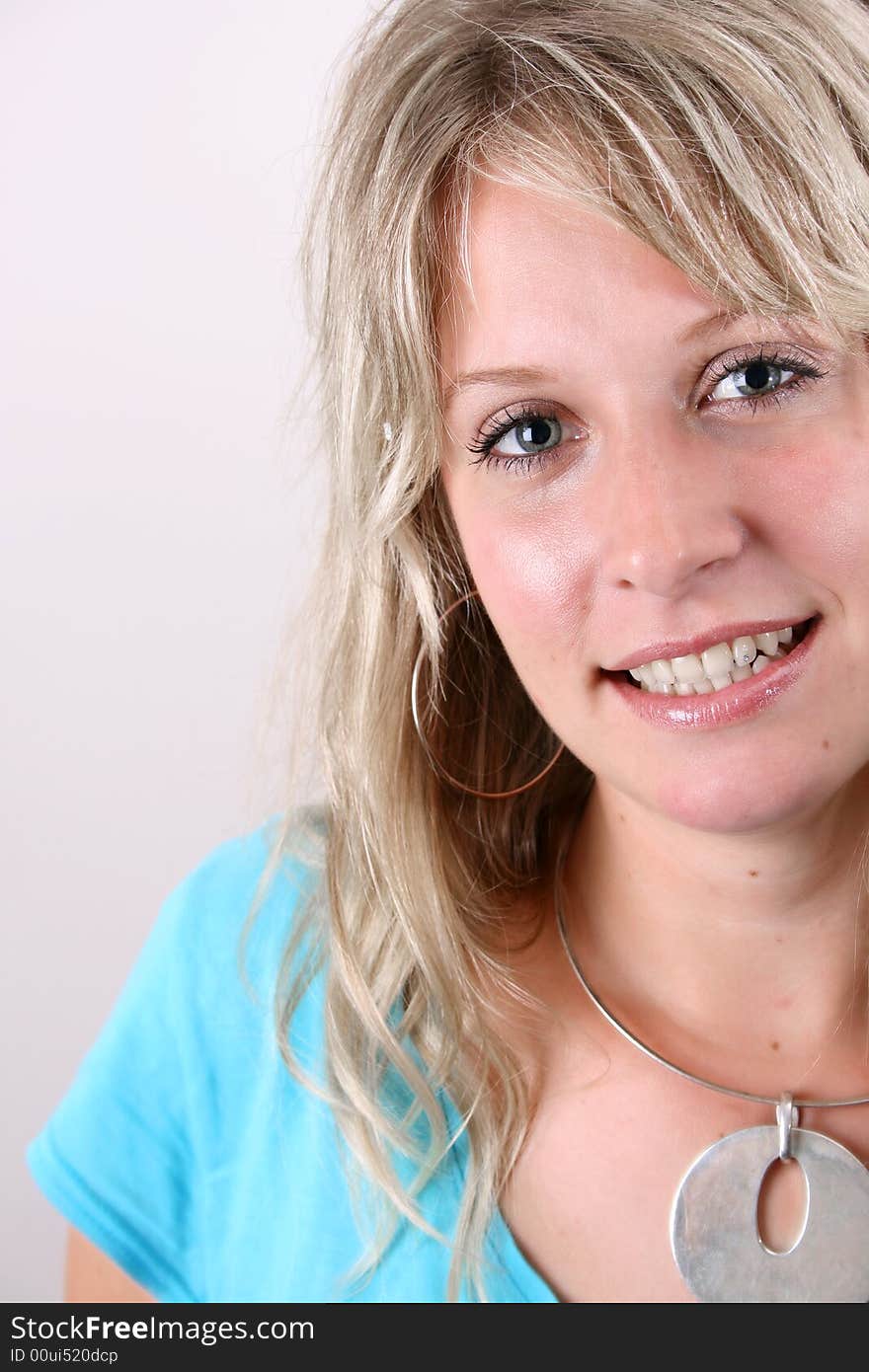 Blond Female model on a white background wearing a blue top. Blond Female model on a white background wearing a blue top