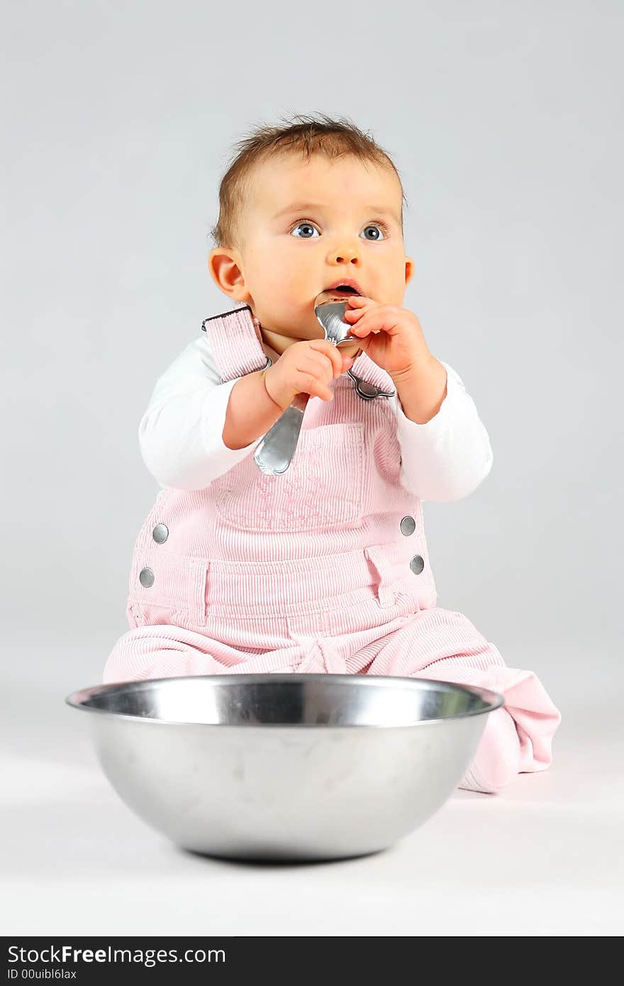 Small baby is sitting with bowl and spoon