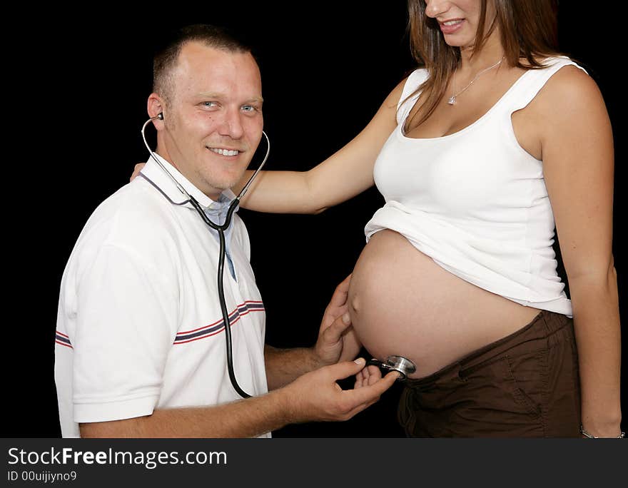 Happy expectant father listening to his wife's pregnant belly with a stethoscope. Happy expectant father listening to his wife's pregnant belly with a stethoscope.