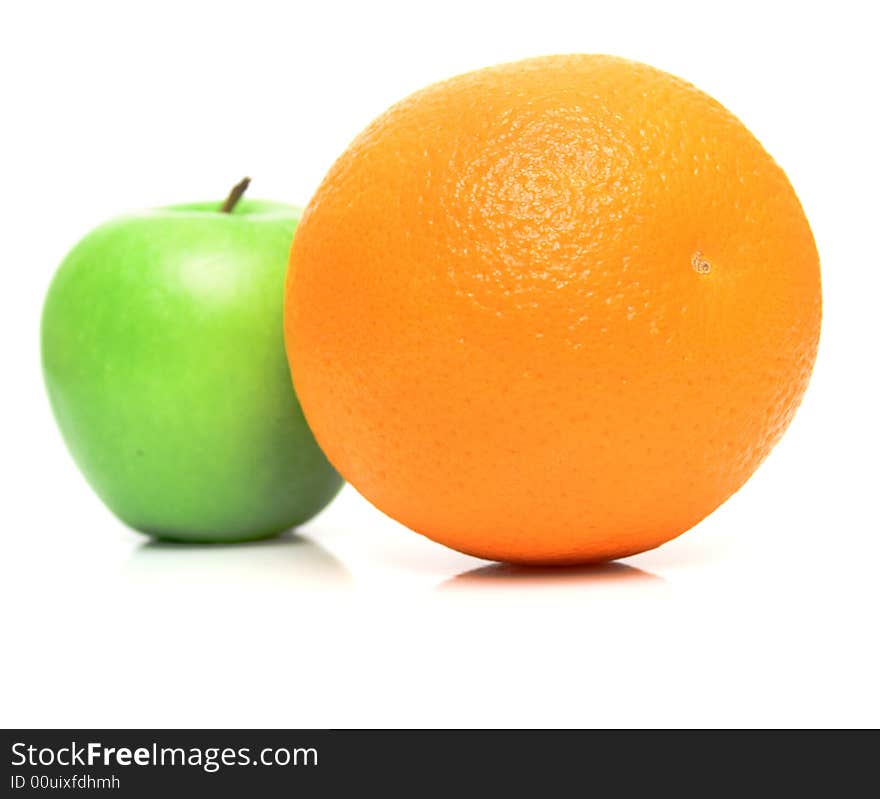 The ripe juicy apple covered by drops of water. Behind of a orange the green apple. Isolation on white, shallow DOF. The ripe juicy apple covered by drops of water. Behind of a orange the green apple. Isolation on white, shallow DOF.