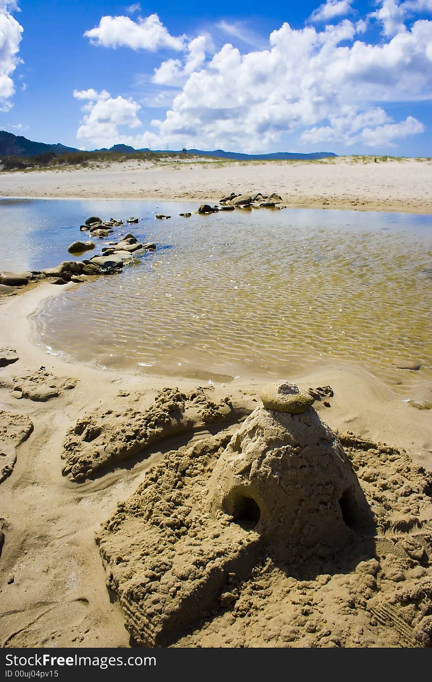 Sand castle in a idyllic beach with aquamarine water and clouds. Sand castle in a idyllic beach with aquamarine water and clouds