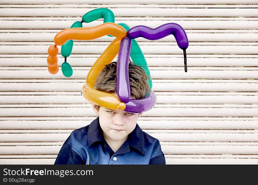 Young boy wearing a balloon hat with an angry face. Young boy wearing a balloon hat with an angry face