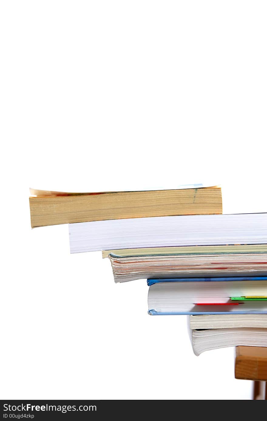 A stack of books sitting on the corner of a desk