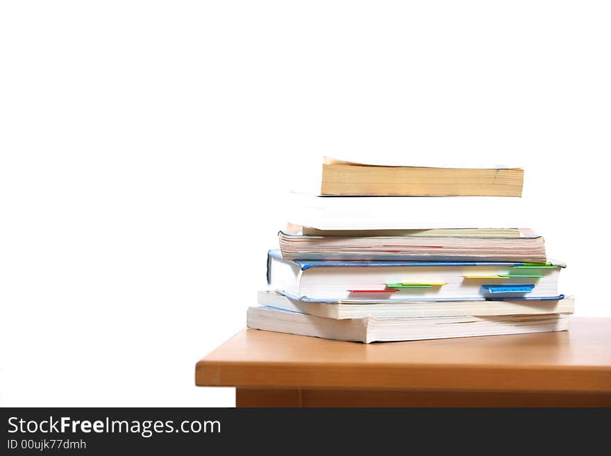 A stack of books sitting on the corner of a desk