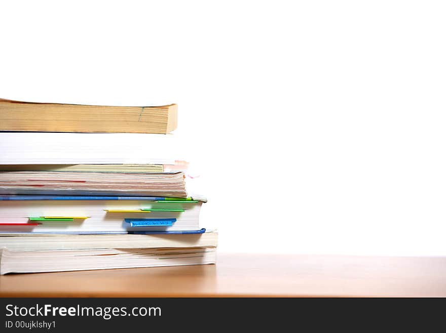 A stack of books sitting on the corner of a desk