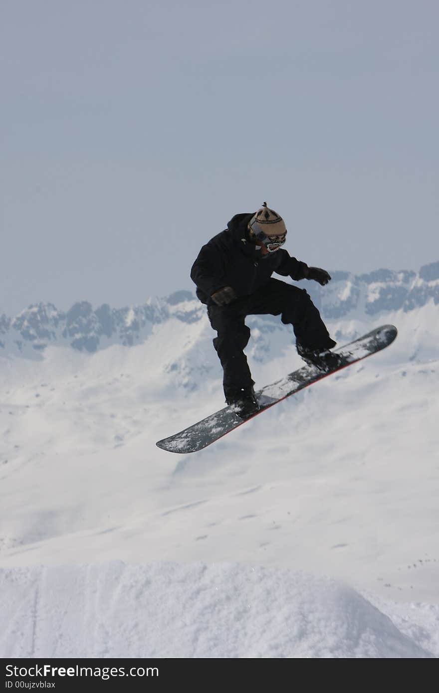 Balancing on his board the snowboarder flys through the air. Balancing on his board the snowboarder flys through the air