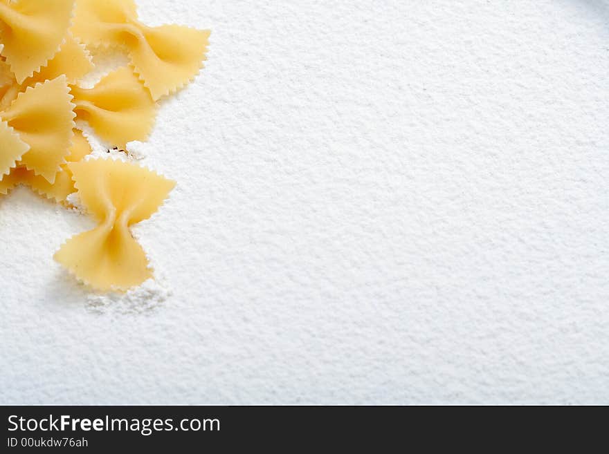 Uncooked macaroni on wheat flour, background