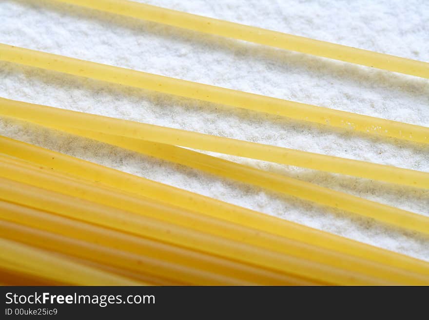 Uncooked macaroni on wheat flour, background