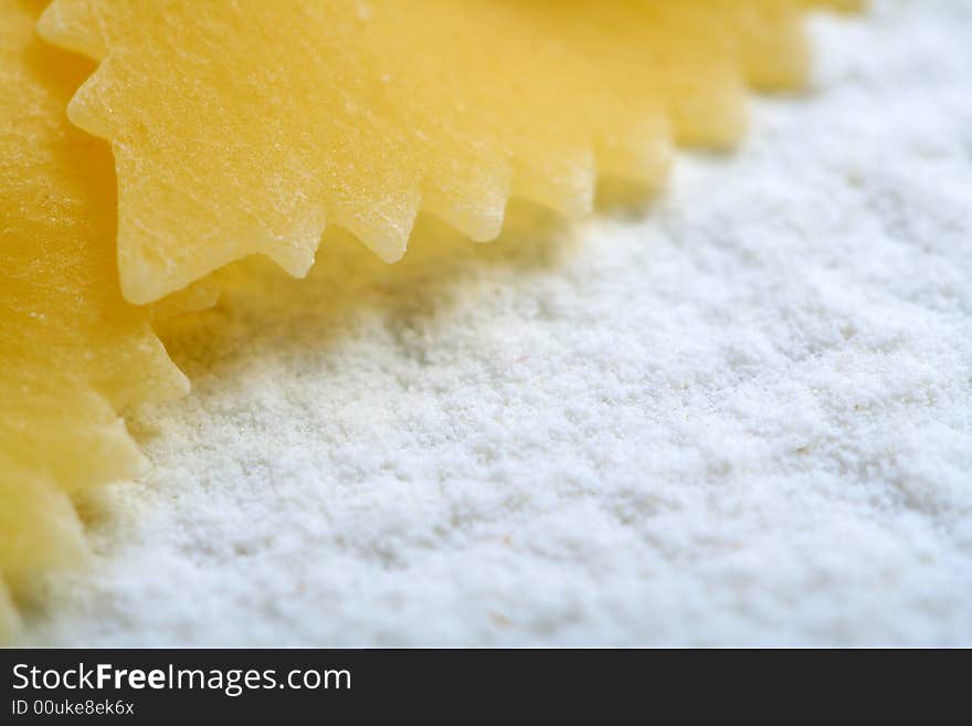 Uncooked macaroni on wheat flour, background