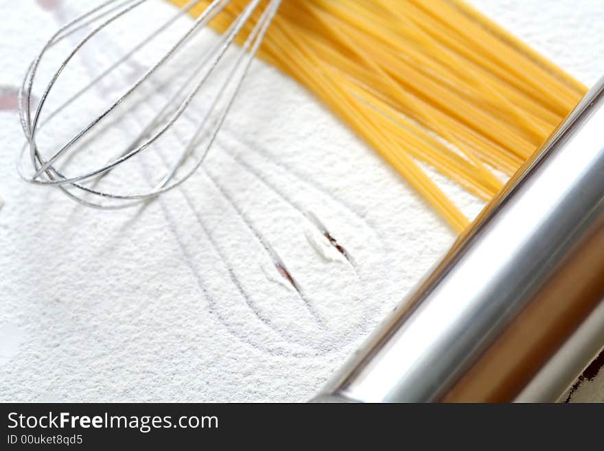 Wire whisk and spaghetti on flour