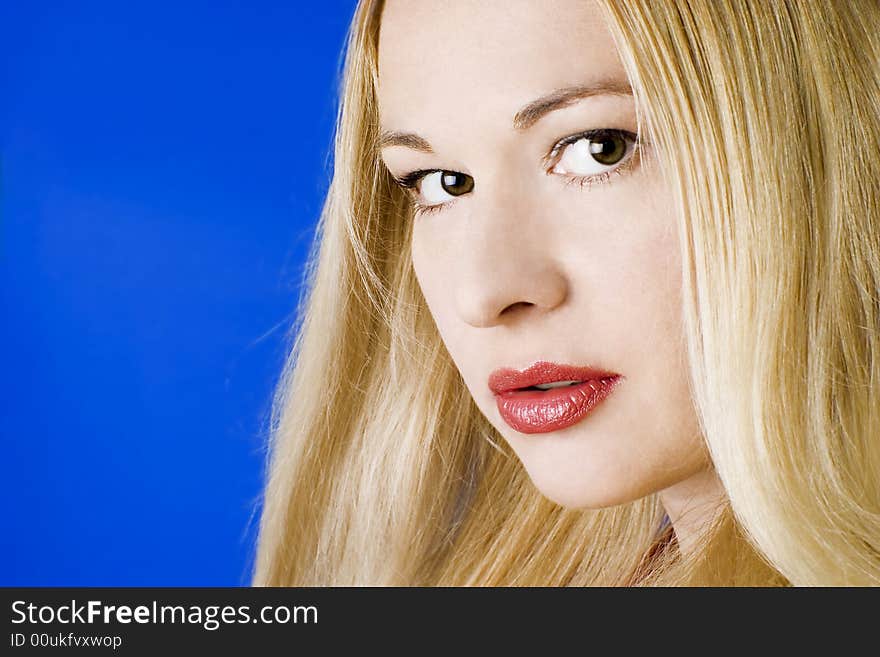 Beautiful young blonde woman with red lips. Blue background.