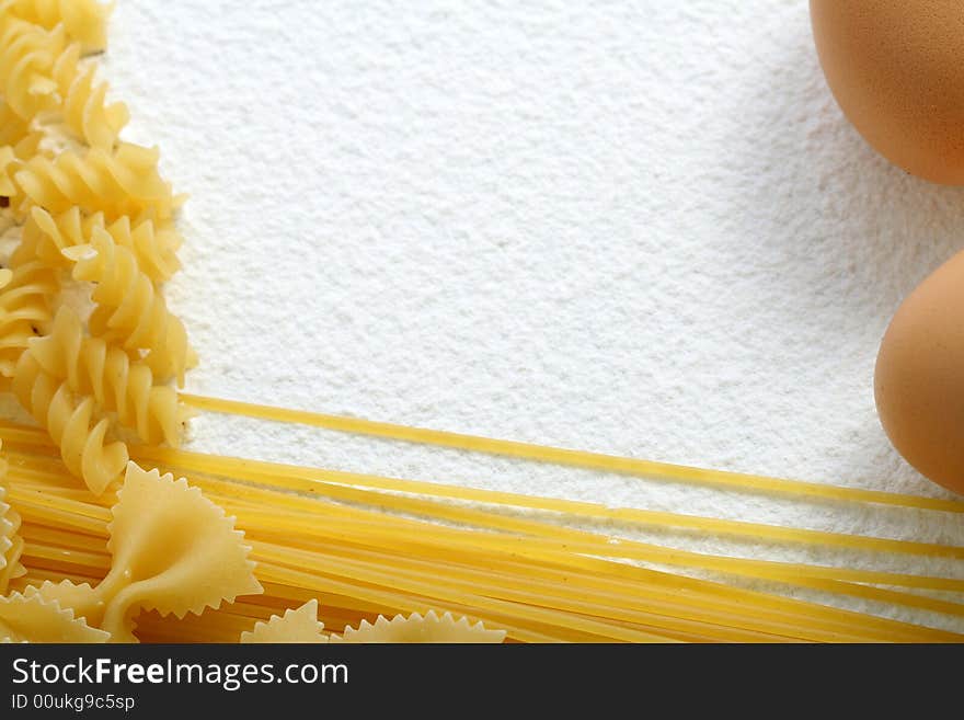 Uncooked macaroni and egg on wheat flour, background. Uncooked macaroni and egg on wheat flour, background