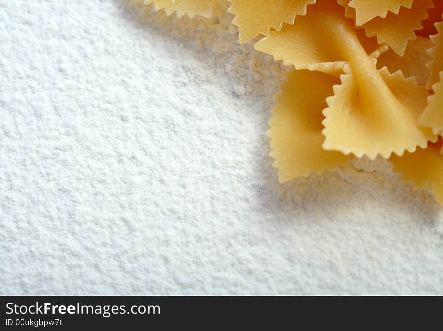 Uncooked macaroni on wheat flour, background