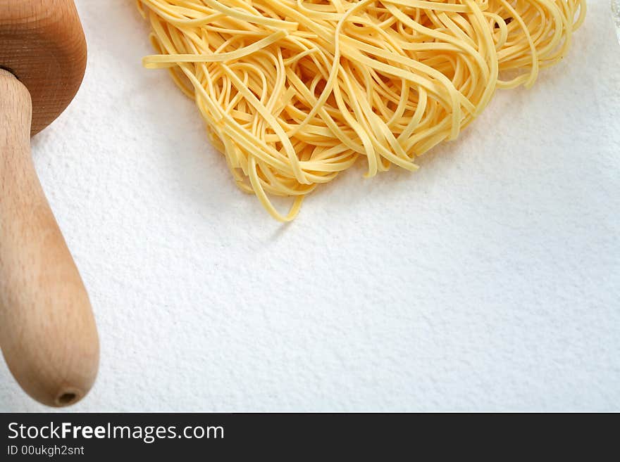 Uncooked noodles and rolling pin on flour