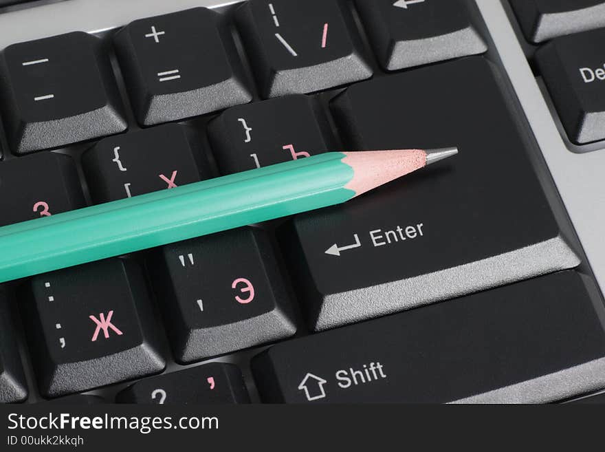 Computer keyboard and green pencil