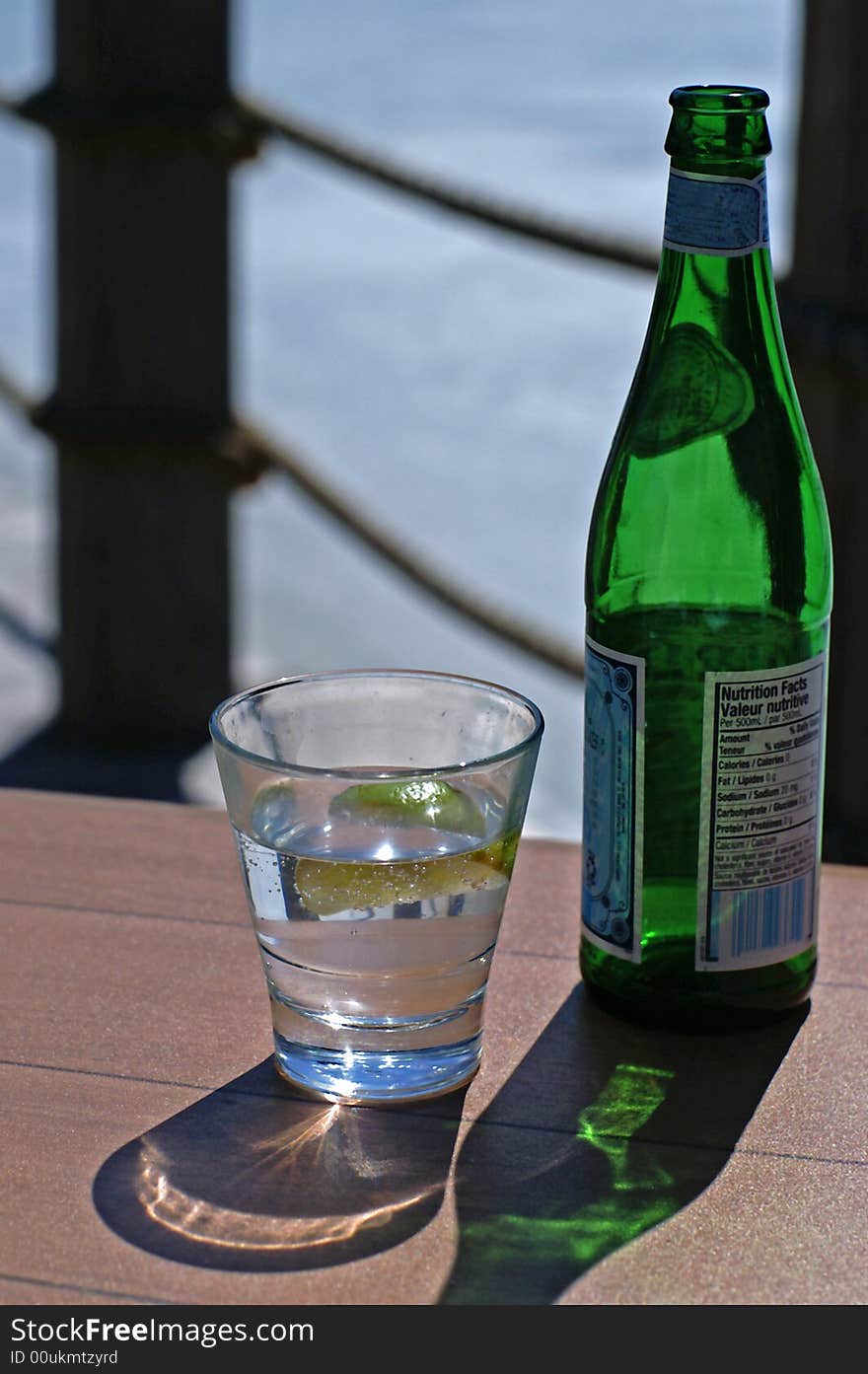 A refreshing glass of bottled water on a table by the dock. A refreshing glass of bottled water on a table by the dock