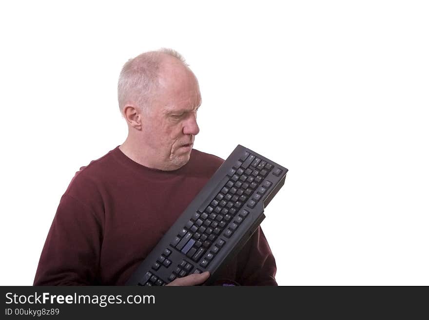 An older man with a computer keyboard looking confused or exasperated. An older man with a computer keyboard looking confused or exasperated