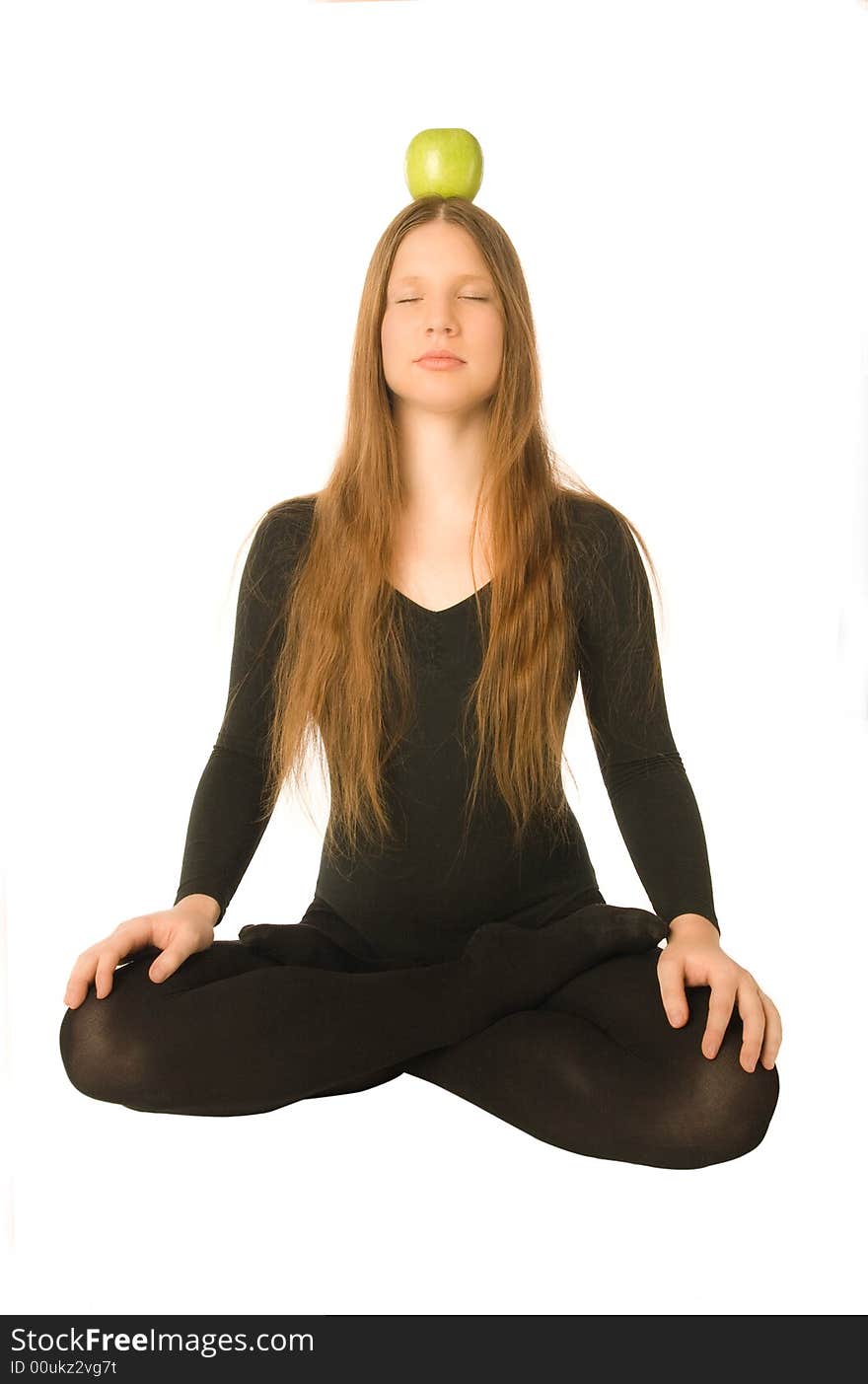 The portrait of a woman in lotus pose with a green apple on her head. The portrait of a woman in lotus pose with a green apple on her head