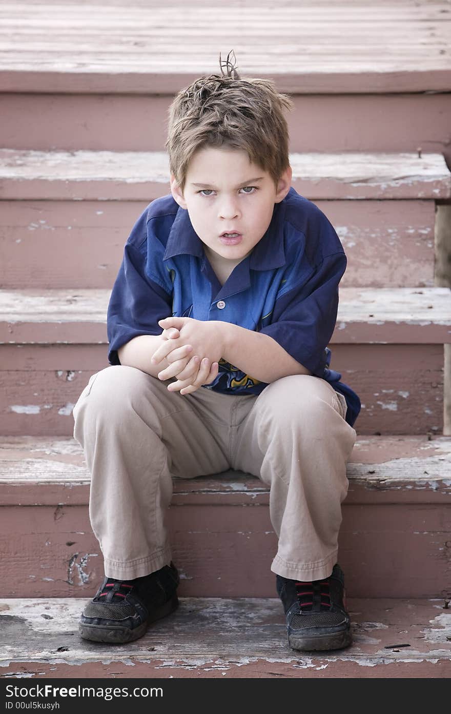 Grumpy Young Boy Sitting on Peeling Stairs. Grumpy Young Boy Sitting on Peeling Stairs