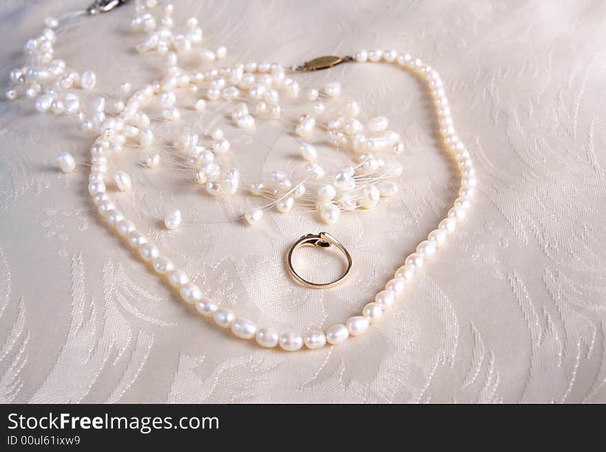 Pearls and rings on satin cushion