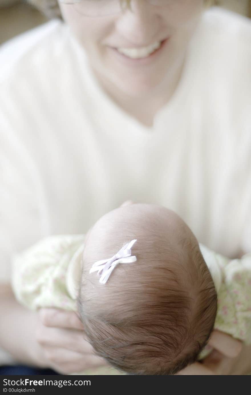 New born baby girl with a bow held by her mother. New born baby girl with a bow held by her mother